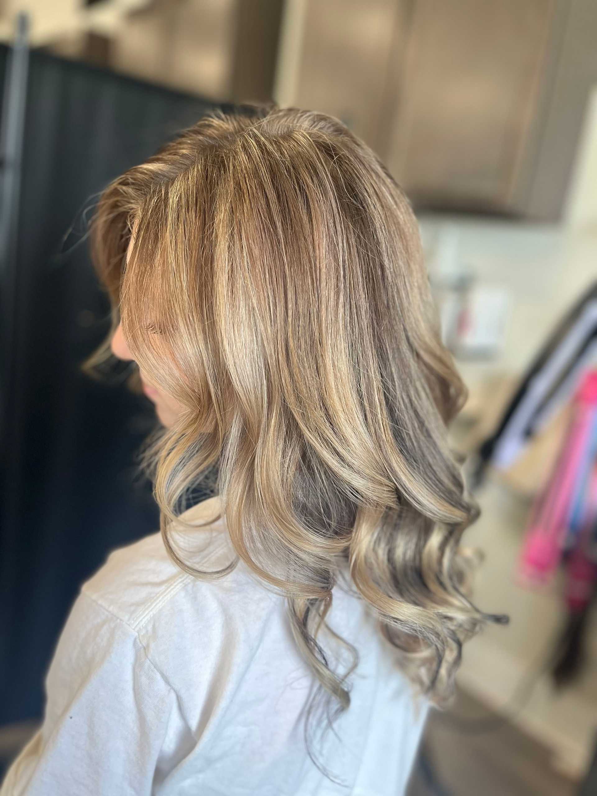 Woman with wavy, blonde highlights hairstyle in a home setting.