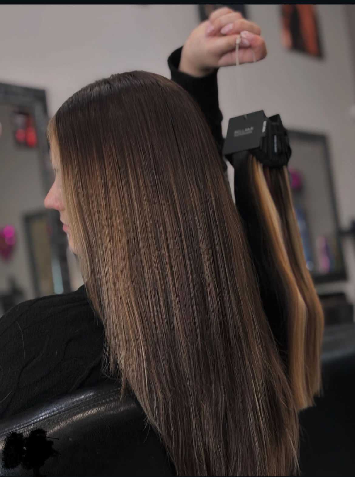 Woman holding a sample of hair extensions with a matching color to her hair.