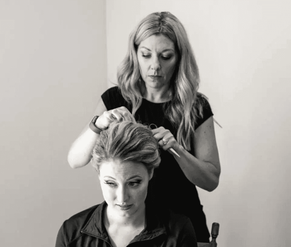 A hairstylist creating an updo for a seated client.